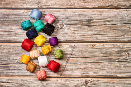 Colored yarn spools and a crochet needle on a wooden background with copy spaceの写真素材