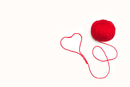 Red wool ball with a heart on a white background with copy space