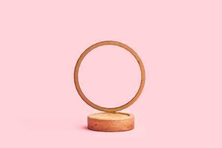 A round wooden base with a round ornament on a pink background