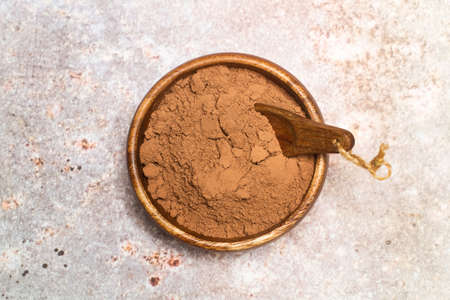 Cocoa powder in a wooden bowl on a marble tableの写真素材