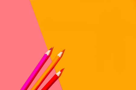 Orange and pink pencils on a pink and orange background in a top viewの写真素材