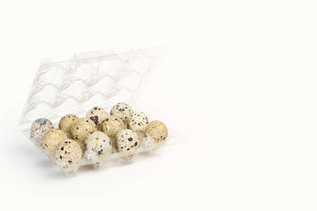 A dozen of quail eggs in a plastic tray on a white background with copy space