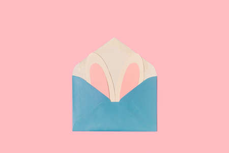 Paper rabbit ears in a blue envelope on a pink background with copy spaceの写真素材