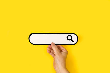 Woman hand holding a blank search bar on a yellow backgroundの写真素材