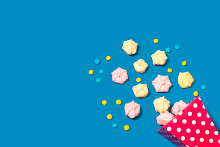 Meringues in a pink bucket and on a blue background with copy spaceの写真素材