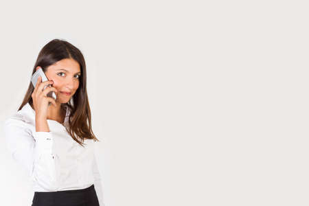 Brunette woman using a smartphone on a white background with copy space