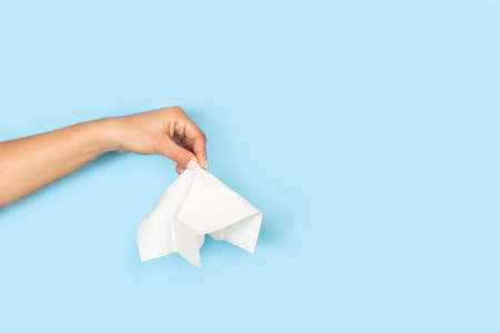 Woman hand holding a tissue on a light blue background