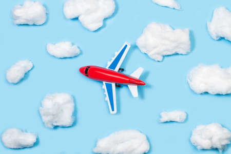Clouds shaped cotton and a toy plane on a blue background with copy space