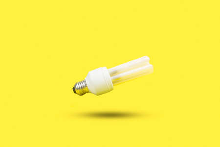 White lightbulb floating on a yellow background with shadow and copy space