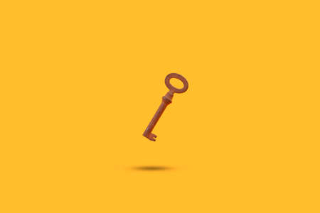 Rusted old metal key floating on a yellow background with shadow and copy space