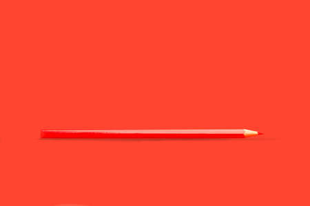 Red pencil on a red background with copy spaceの写真素材