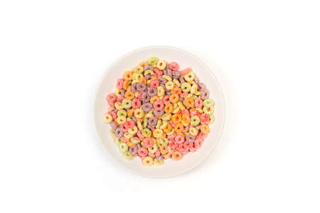 Fruit flavor colored cereals in a white plate on a white background in a top view