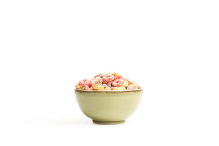 Fruit flavor colored cereals in a ceramic bowl on a white background with copy space