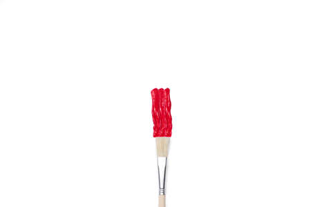 Artistic paintbrush and a red paint stroke on a white background with copy spaceの写真素材