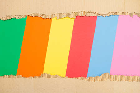 Pieces of ripped cardboard on a multicolored background with copy spaceの写真素材