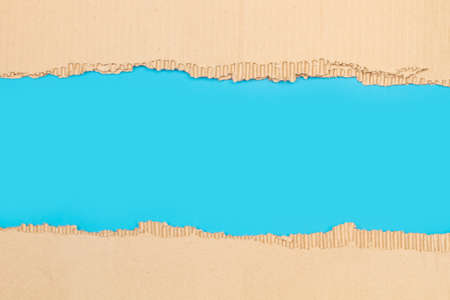 Pieces of ripped cardboard on a blue background with copy spaceの写真素材