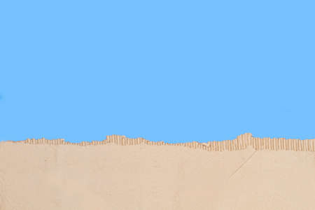 Piece of ripped cardboard on a blue background with copy spaceの写真素材