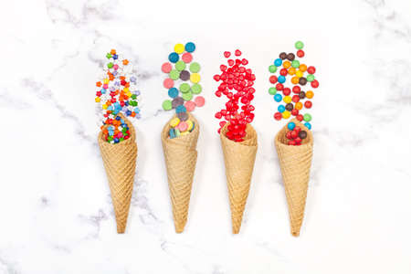Multicolored candies in wafer cones on a marble kitchen counterの写真素材