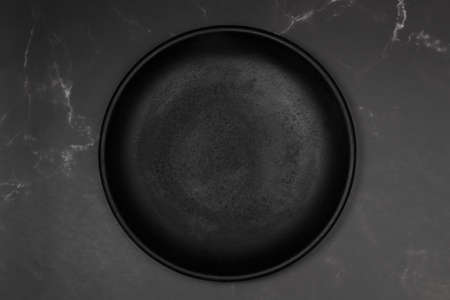 Black flat plate on a black marble kitchen counter in a top viewの写真素材