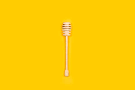 A wooden honey dipper on a yellow background with copy spaceの写真素材