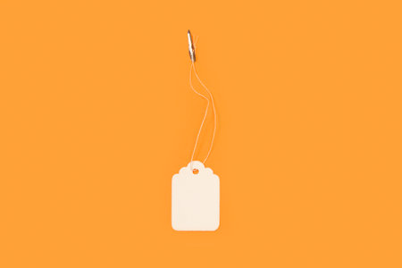 Blank white cardboard label on a orange background with copy spaceの写真素材