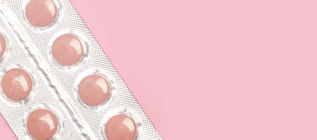 Medical pills in a blister on a pink background with copy spaceの写真素材