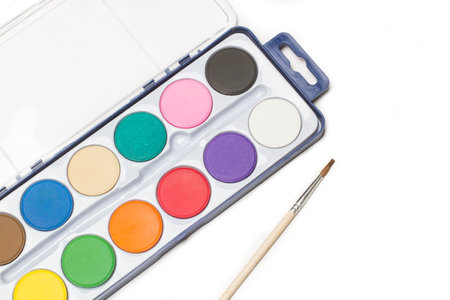 A palette of watercolors and a paintbrush on a white background with copy spaceの写真素材