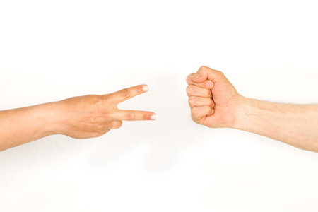 Man and woman hands doing rock, paper, scissors game on a white background with copy spaceの写真素材
