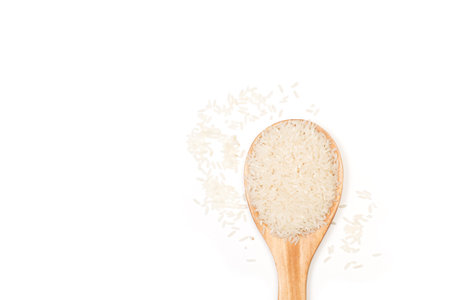 Raw rice in a wooden spoon and on a white background with copy spaceの写真素材
