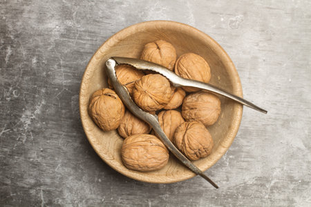 Walnuts in a wooden bowl and a nutcracker on a marble kitchen countertop in a top viewの写真素材