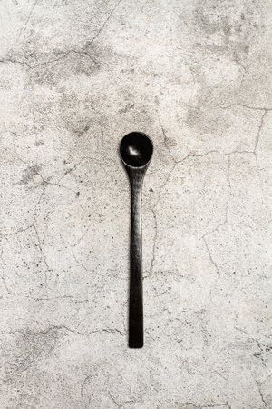 A black spoon on a gray stone kitchen counter background with copy spaceの写真素材