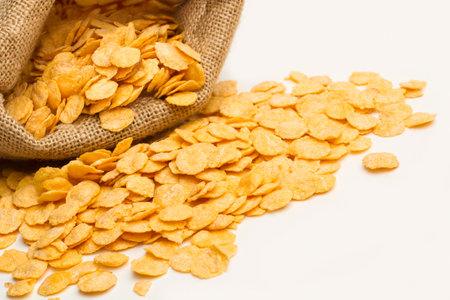 Corn flakes in a burlap sack and on a white background with copy space