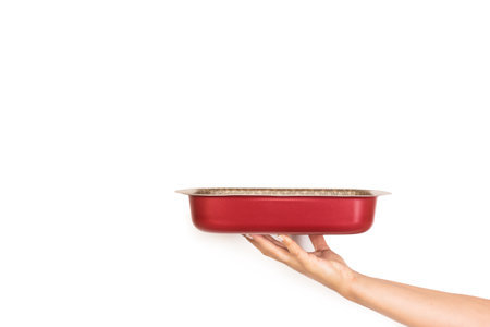 Woman hand holding a metal baking dish on a white background with copy spaceの写真素材