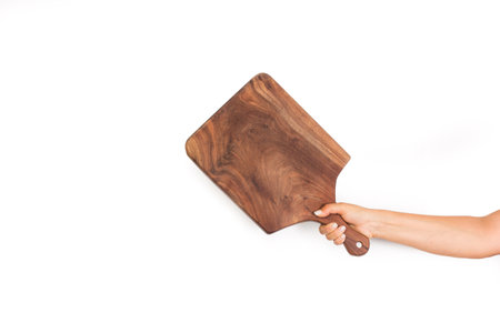Woman hand holding a brown wooden kitchen board on a white background with copy space