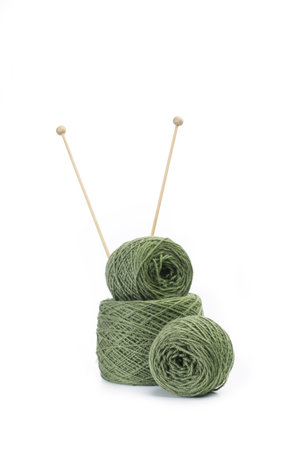 Green wool balls and knitting needles on a white background with copy space