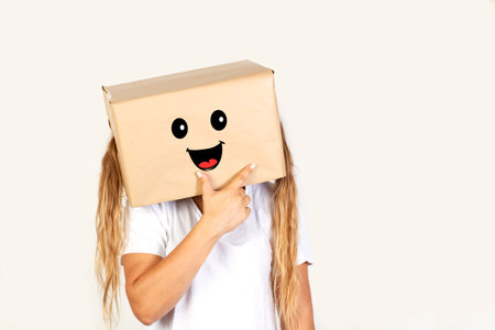 Woman with her head in a box and happiness gesture standing on a white background with copy spaceの写真素材