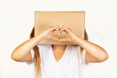 Woman with her head in a box and hands in heart shape on a white background with copy spaceの写真素材
