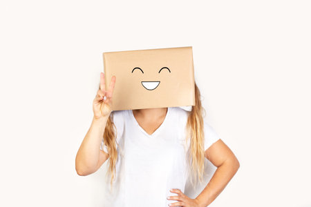 Woman with her head in a box and victory gesture standing on a white background with copy spaceの写真素材