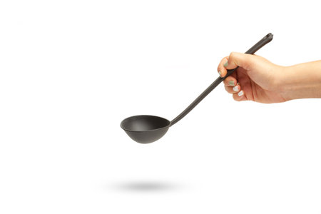 Woman hand holding a black plastic ladle on a white background with copy spaceの写真素材