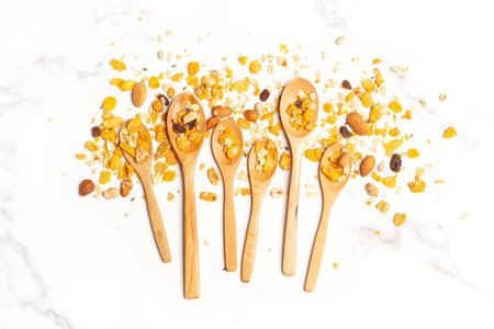 A heap of granola and wooden spoons on a white marble kitchen counter with copy space
