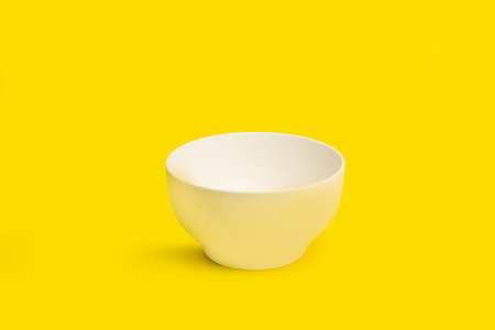 Black ceramic bowl on a yellow background with copy spaceの写真素材