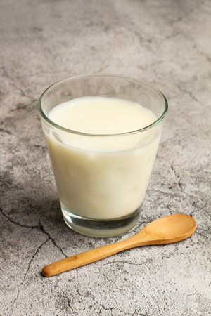 A glass of milk and a wooden spoon on a marble kitchen coubterの写真素材