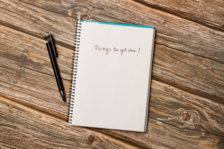 Things to get done write on a page of a spiral notebook on a wooden background in a top view