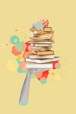 A hand holding books with a reading brain on the top on a colored background with copy spaceの写真素材
