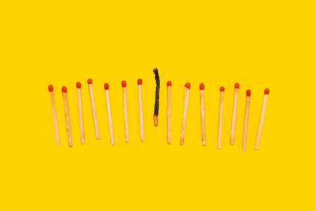 Wooden matches sticks, one burned on a yellow background with copy spaceの写真素材