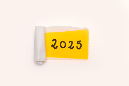 2025 handwritten on a yellow paper behind a white torn paper with copy spaceの写真素材
