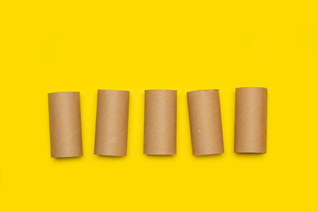 Cardboard toilet paper rolls without paper on a yellow background with copy spaceの写真素材