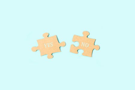 Yes and no single words written on brown puzzle pieces on a light blue background with copy spaceの写真素材