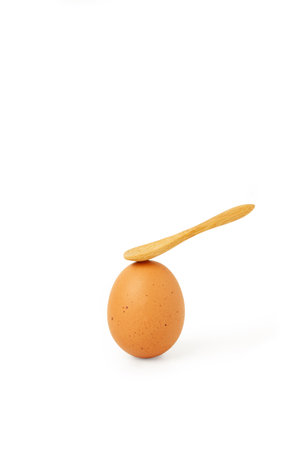 A brown egg with a wooden spoon on it on a white background with copy spoaceの写真素材