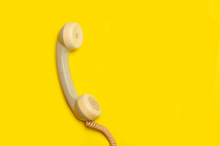 Vintage telephone handset on a yellow background with copy spaceの写真素材